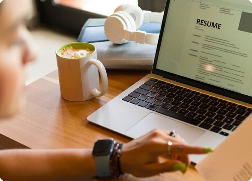 Person reviewing a resume on a laptop beside a coffee mug