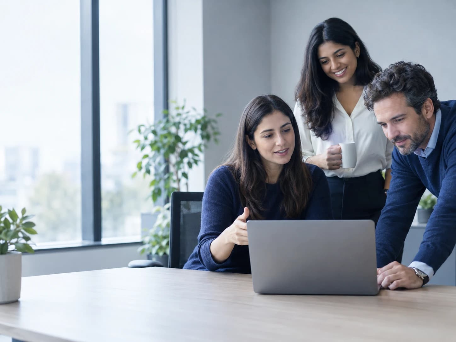 A recruiter reviewing a candidate profile on a laptop with two colleagues in a bright office